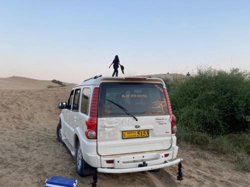 a person standing on top of a van in the desert at Blue Eye Hostel in Jaisalmer