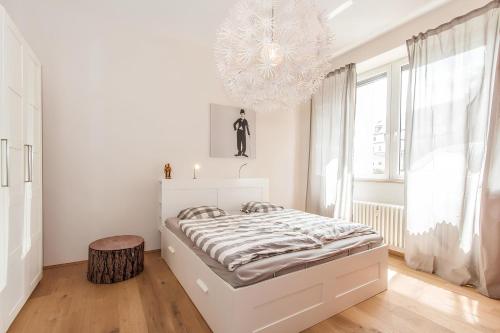 a white bedroom with a bed and a chandelier at Wohnen am Kulturspeicher mit eigenem Parkplatz in Würzburg