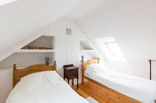two beds in a room with white walls at The Workshop- Eco Cottage by the Coastal Path in Goodwick