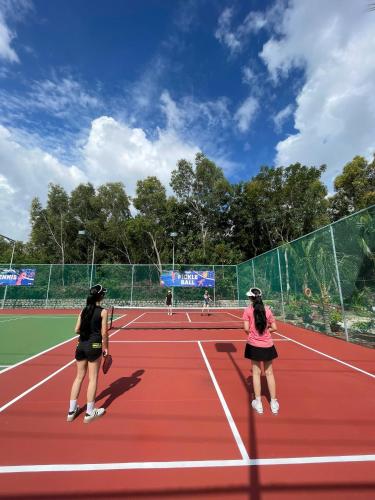 two women playing tennis on a tennis court at Sonata Resort & Spa in Phan Thiet