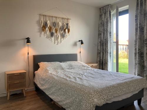 a bedroom with a bed and a window and a chandelier at 4-person chalet Albatros by the water with parking space in Anjum