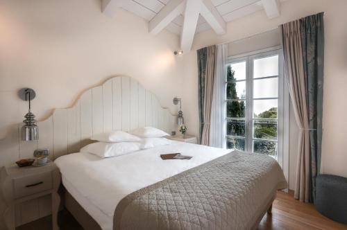 艾日Hôtel Eze Hermitage的卧室里有一张白色的大床，床边有一扇窗户