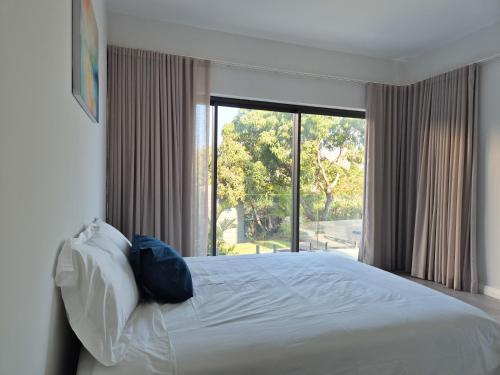 a bedroom with a white bed with a large window at Uptamarin B1 in Rivière Noire