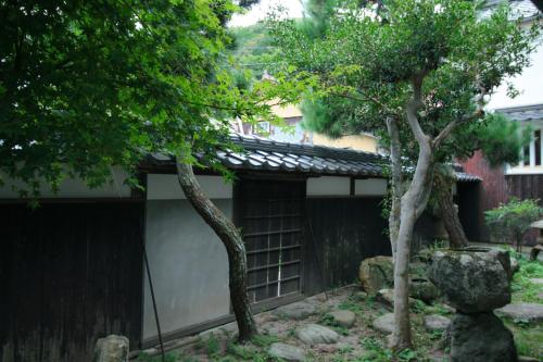 a garden with two trees and a building at HÏSOM 湯里 in Oda
