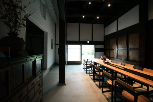 a dining room with a long table and chairs at HÏSOM 湯里 in Oda