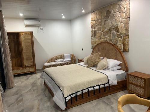a bedroom with a bed and a stone wall at Palacio Balangan Villa in Uluwatu
