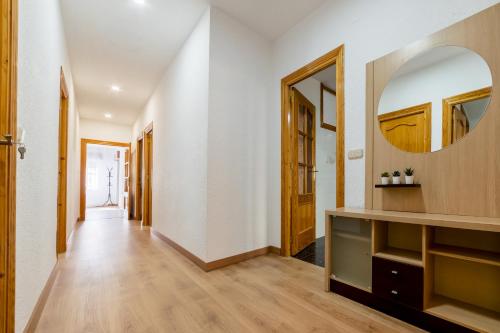 a hallway with a mirror and white walls and wooden floors at Casa LAS TORRES in Dúdar