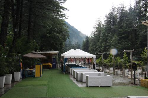 a group of tables with a tent on a grass field at Moksha Riverside Resort in Kasol