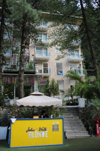 a table with an umbrella in front of a building at Moksha Riverside Resort in Kasol