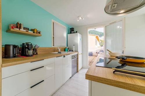 a kitchen with white cabinets and a blue wall at Évasion à Carqueiranne - Animal ok & terrasse in Carqueiranne