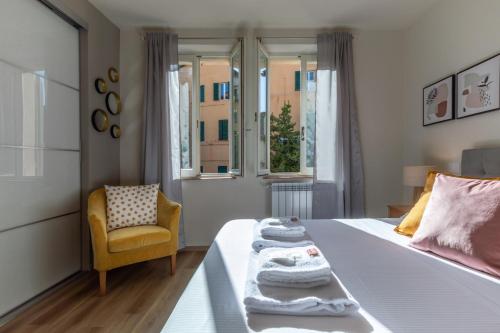 a bedroom with a bed and a chair and windows at Sunlit Heaven in Siena