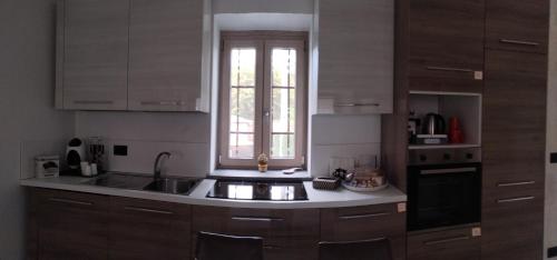 a kitchen with wooden cabinets and a sink and a window at La Rocchetta - Ai piedi del Parco Naturale in Cavour
