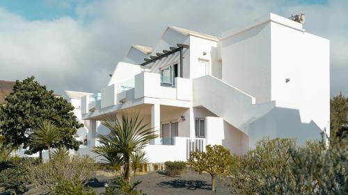 a white house with trees in front of it at Labranda Alyssa Suite Hotel in Playa Blanca