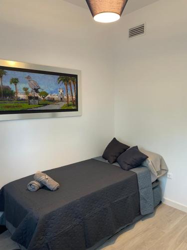 a bed in a room with a picture on the wall at Casa Gloria in El Puerto de Santa María