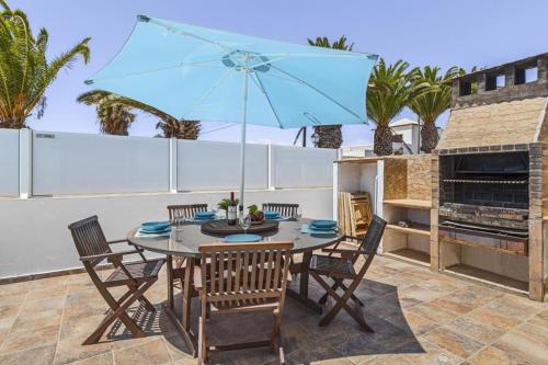 a table and chairs with a blue umbrella on a patio at Villa Palacios Herrero in Tahiche