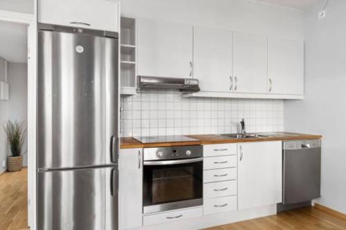 a kitchen with a stainless steel refrigerator and white cabinets at Wow, Apartment with great location in Oslo