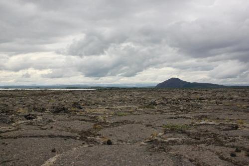 a desolate field with a mountain in the background at Aska, Modern Cabin in Myvatn