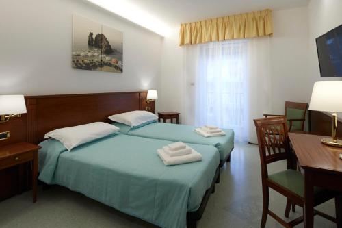 a hotel room with two beds and a desk and a table at Hotel Villa Adriana in Monterosso al Mare