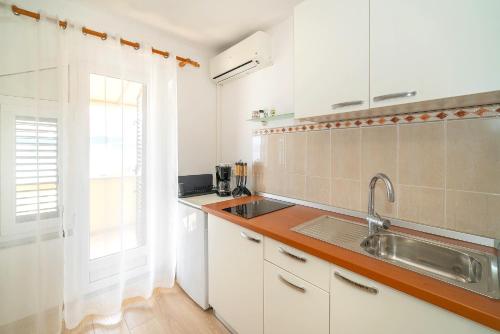 a kitchen with white cabinets and a sink and a window at Studio Apartments Cavrak with Terrace in Baška