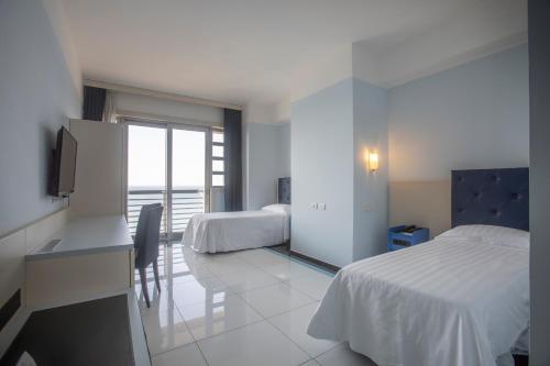 a bedroom with two beds and a desk and a television at Grand Hotel Salerno in Salerno