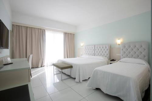 a hotel room with two beds and a television at Grand Hotel Salerno in Salerno