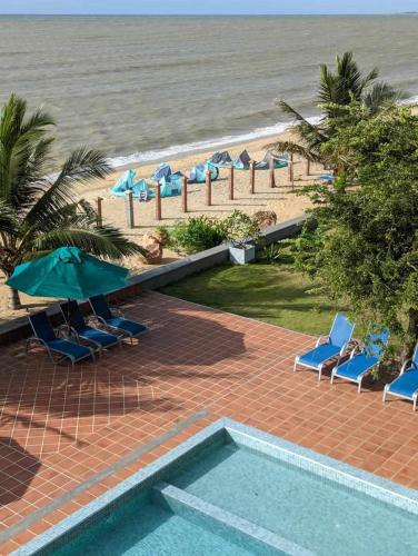 a pool with chairs and umbrellas next to the beach at Hiru Beach Resort in Kalpitiya