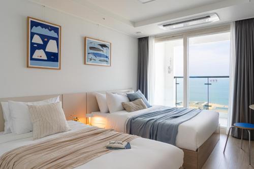 two beds in a hotel room with a view of the ocean at Urbanstay Sokcho Deungdae Beach in Sokcho