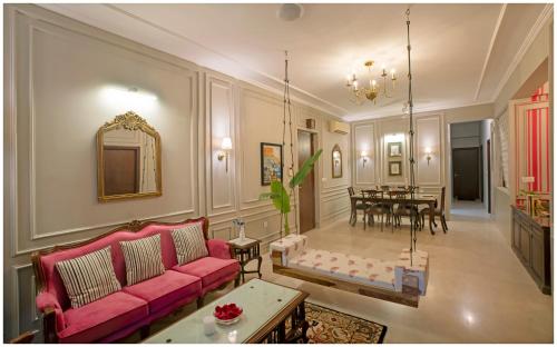 a living room with a pink couch and a dining room at Luxury Heritage Umaid 3BHK Apartment Jodhpur in Jodhpur