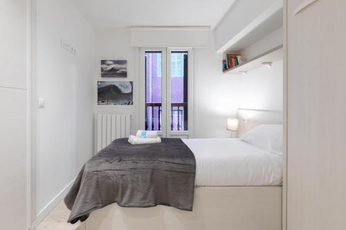 a white bedroom with a bed and a window at Kiriki - baskeyrentals in Zarautz