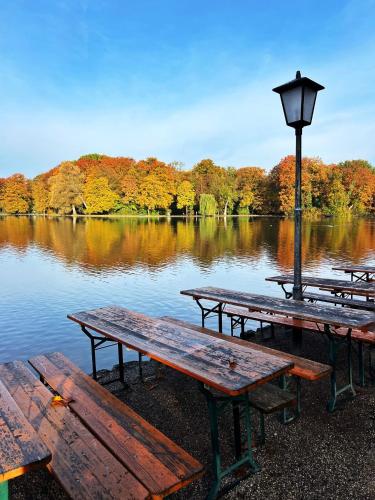 a group of picnic tables in front of a lake at Hotel Occam in Munich
