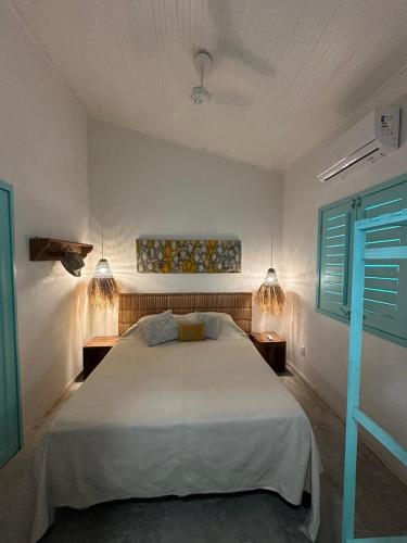 a bedroom with a large white bed and two tables at Vila Almar in Taíba
