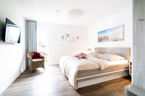 a bedroom with a large bed and a chair at Seebreeze 50 2 N in Wangerland