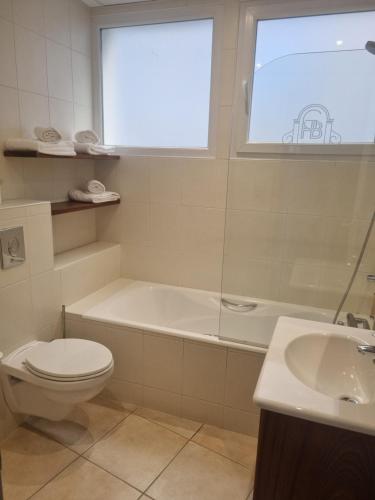 a bathroom with a tub and a toilet and a sink at Best Western Grand Hotel de Bordeaux in Aurillac