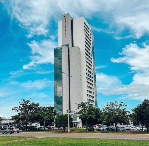 un alto edificio bianco con auto parcheggiate in un parcheggio di Inova Flat no centro a Palmas