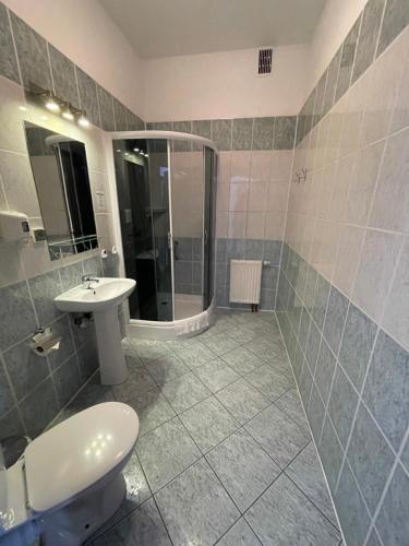a bathroom with a shower and a toilet and a sink at Hotel Biały Domek in Wałcz