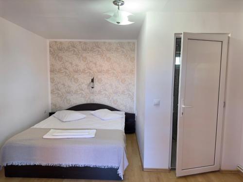 a bedroom with a bed with a white blanket and a door at Marginimea Sibiului - Pensiunea Darian & David in Orlat