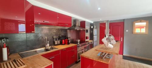 une cuisine avec des armoires rouges et un évier dans l'établissement CHALET COOP - A - 10 pers, à Le Freney-dʼOisans