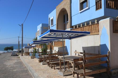 a row of tables with blue umbrellas on a building at Imsouane WOOD HOUSE in Imsouane