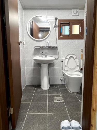 a bathroom with a toilet and a sink and a mirror at Gudeok Guesthouse in Seogwipo