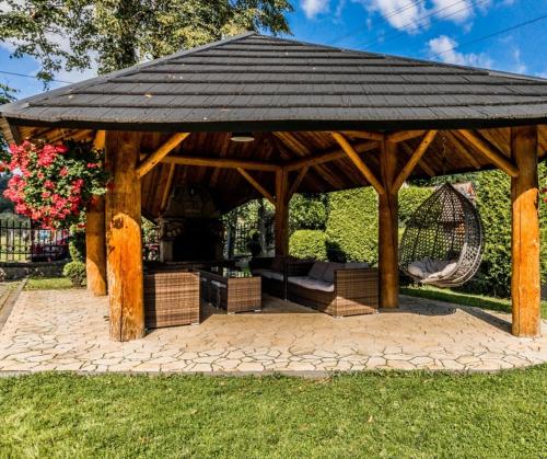 a wooden gazebo with a bench and a swing at Tatrzański Dworek in Biały Dunajec