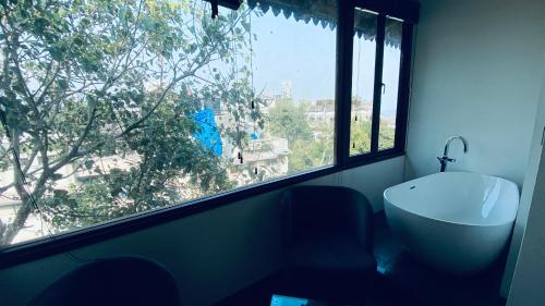a bathroom with a large window and a bath tub at Gulf Hotel Mumbai- The Boutique Hotel Colaba Mumbai in Mumbai