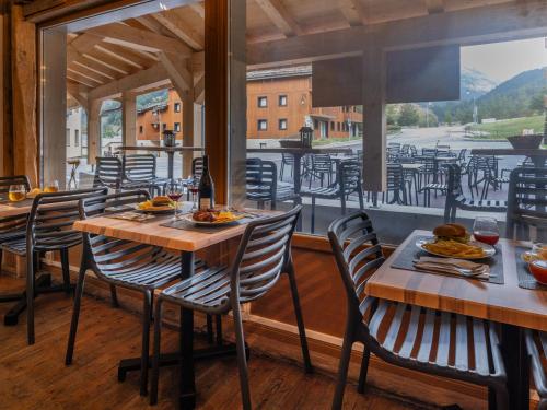 un restaurant avec des tables et des chaises sur un balcon dans l'établissement SUNWEB Les Terrasses de Termignon - Val-Cenis, à Termignon