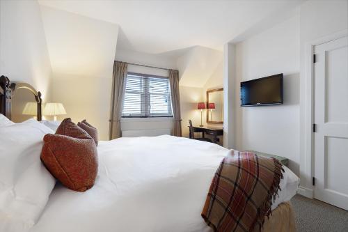 ein Schlafzimmer mit einem weißen Bett und einem Fernseher an der Wand in der Unterkunft Ugadale Cottages in Machrihanish
