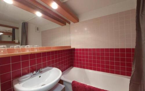 a bathroom with a tub and a sink and red tiles at Duplex arcs 1800 aux pieds des pistes in Arc 1800