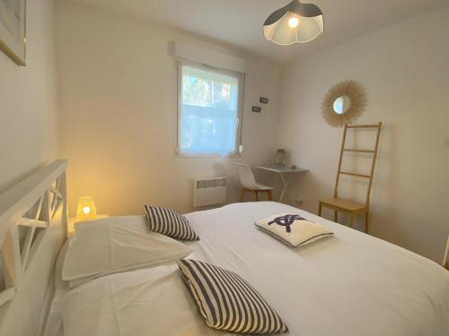 une chambre avec un lit blanc avec deux oreillers dessus dans l'établissement Appartement de la mer, à Jullouville