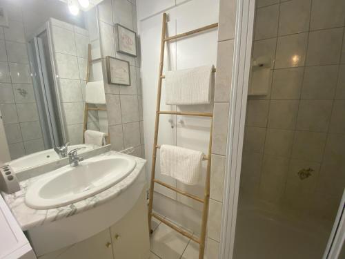 une salle de bain blanche avec un lavabo et une douche dans l'établissement Appartement de la mer, à Jullouville