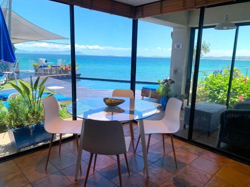 a dining room with a table and chairs and the ocean at 185 on BEACH Boutique Suites in Gordonʼs Bay