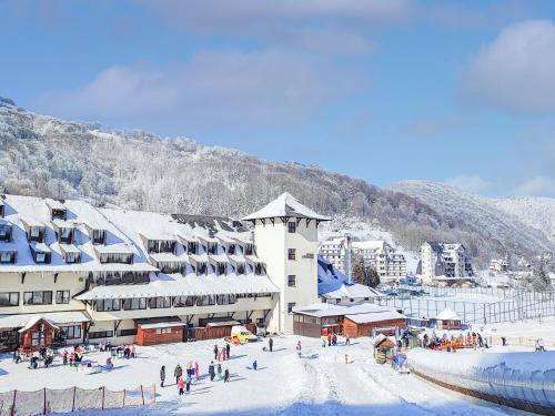 a group of people in the snow in front of a building at Hotel Junior in Kopaonik