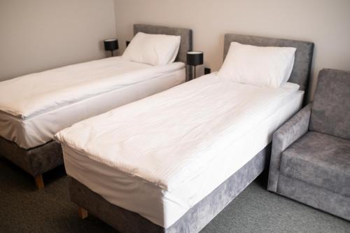 two beds and a chair in a room at Hotel Igloo in Krotoszyn