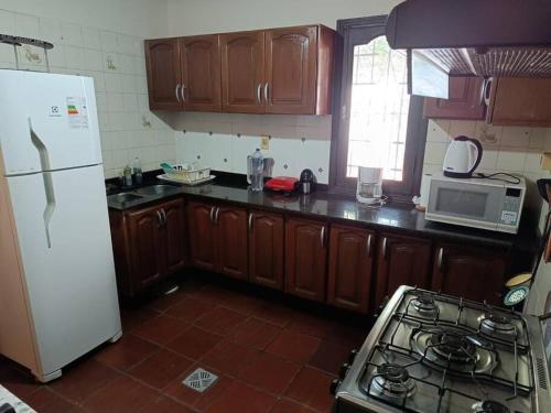 a kitchen with wooden cabinets and a white refrigerator at Casa entera con jardín en Luque! in San Lorenzo